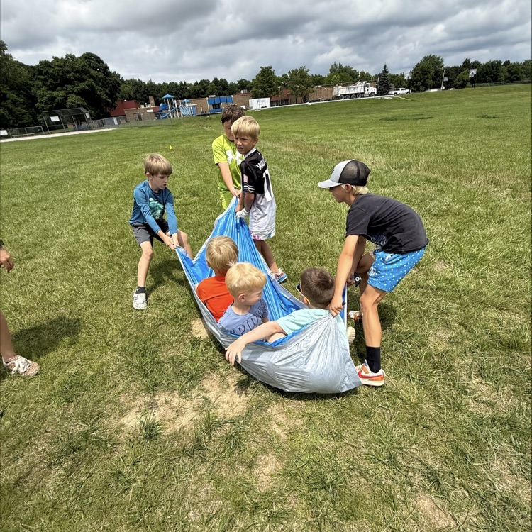 kids pulling other kids around in the grass on a tarp