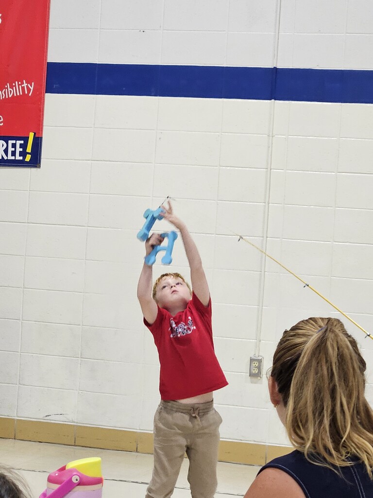 child catching foam letters from a fishing pole