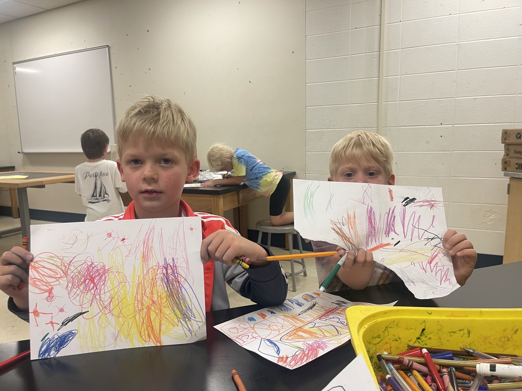 2 boys holding up drawings