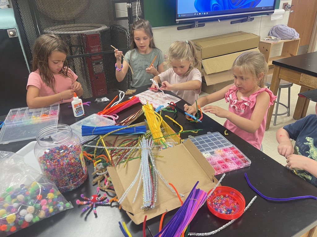 girls sitting around a table doing crafts