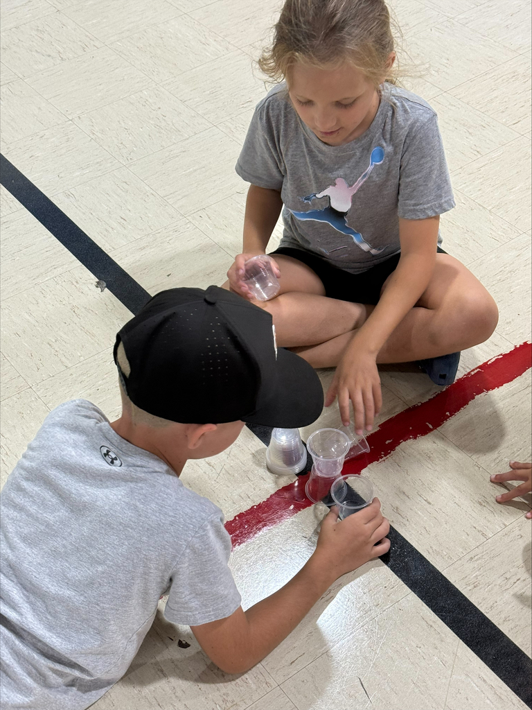 kids playing with cups on a gym floor