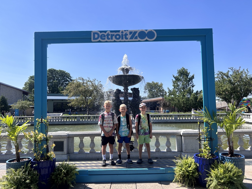 3 boys posing in front of a Detroit Zoo sign