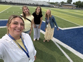 4 women posing on a football field