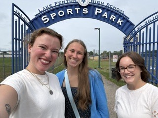 3 women posing in front of a Lake Fenton Sports Park sign