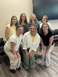 7 women posing in a board room