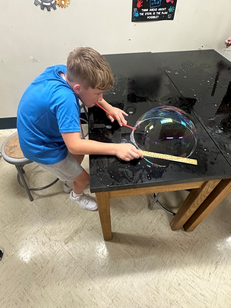 student making large bubbles on a black table