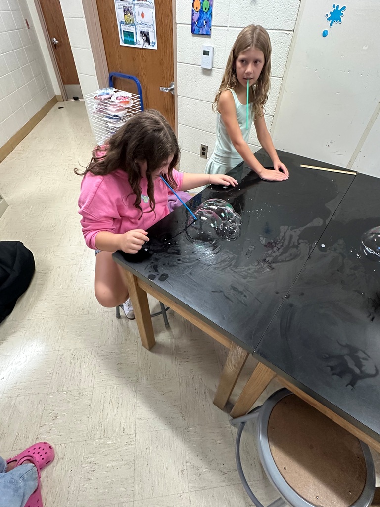 student making large bubbles on a black table