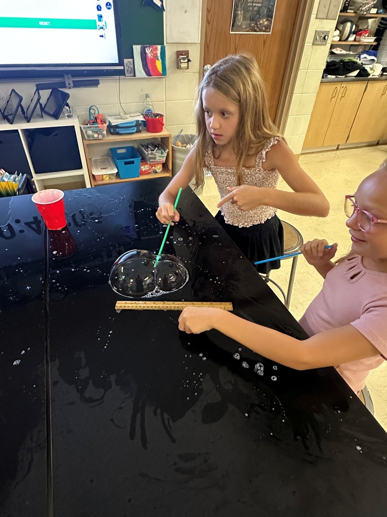 student making large bubbles on a black table