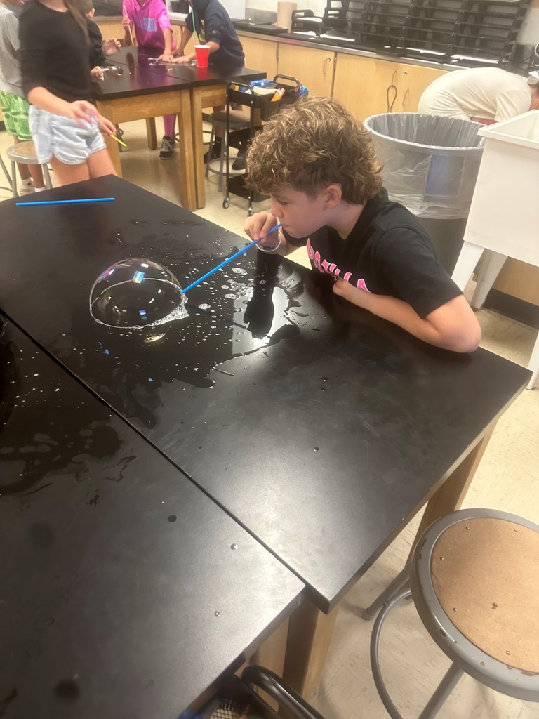 student making large bubbles on a black table