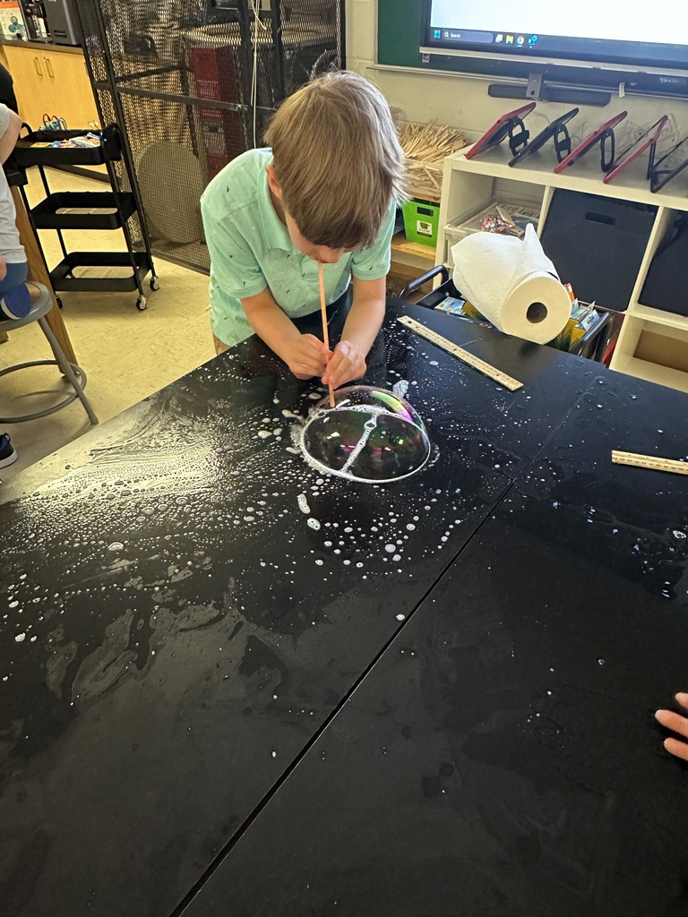 student making large bubbles on a black table