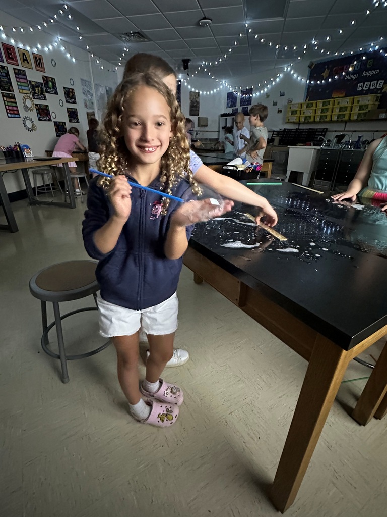 student making large bubbles on a black table