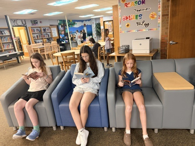 3 girls sitting in chairs reading