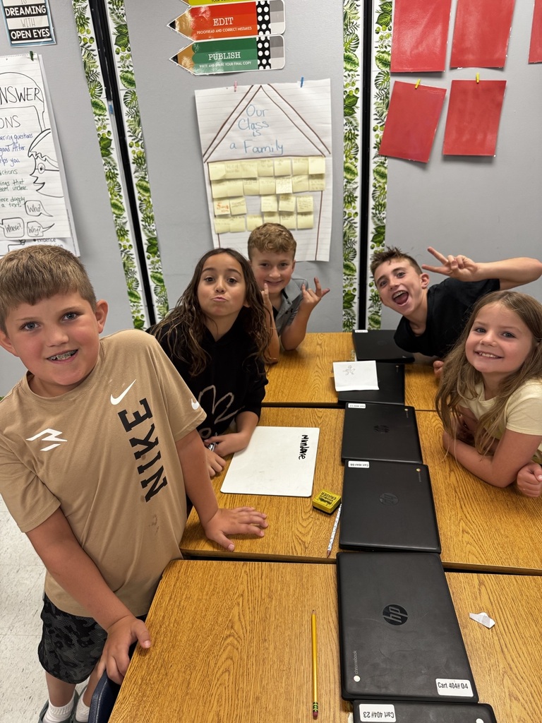 5 kids sitting around a group of desks