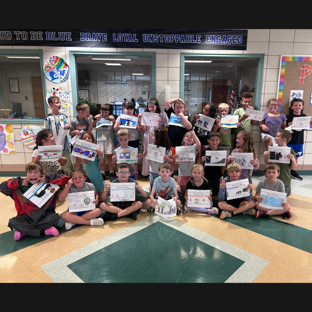 class of children holding drawings and making funny faces