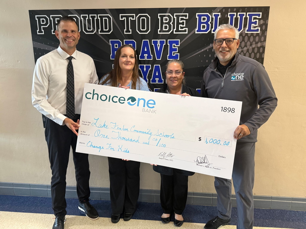 4 adults holding a giant check in front of a Proud to be Blue sign