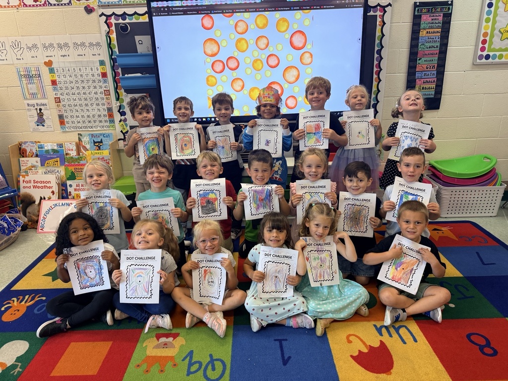group of children in a classroom holding up pictures