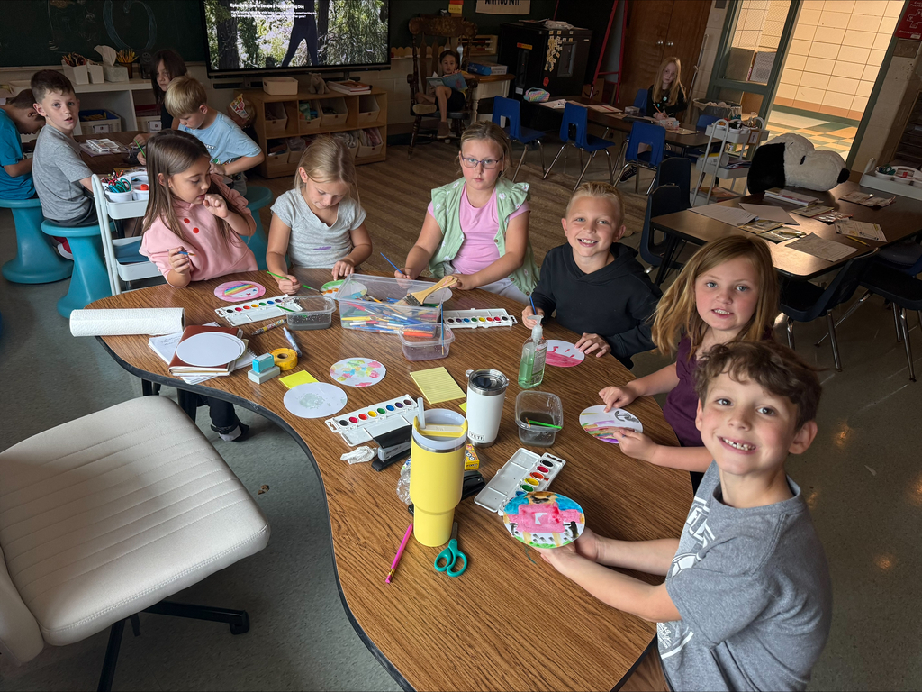 group of students sitting at a table ion a classroom painting with watercolors