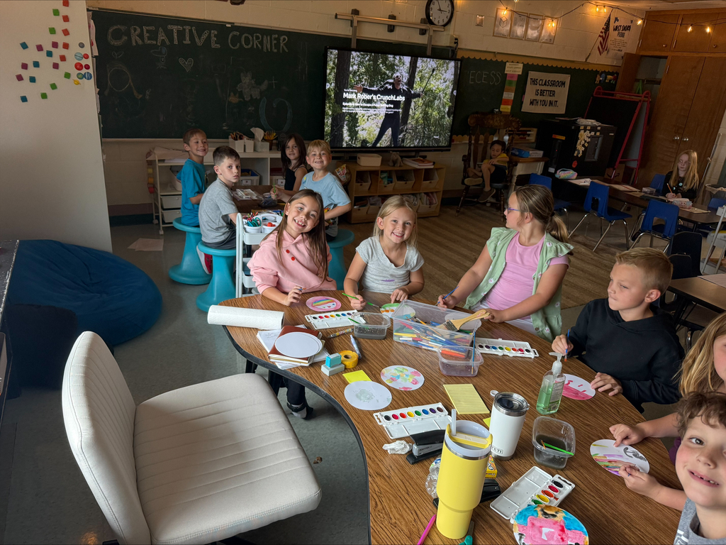 group of students sitting at a table ion a classroom painting with watercolors