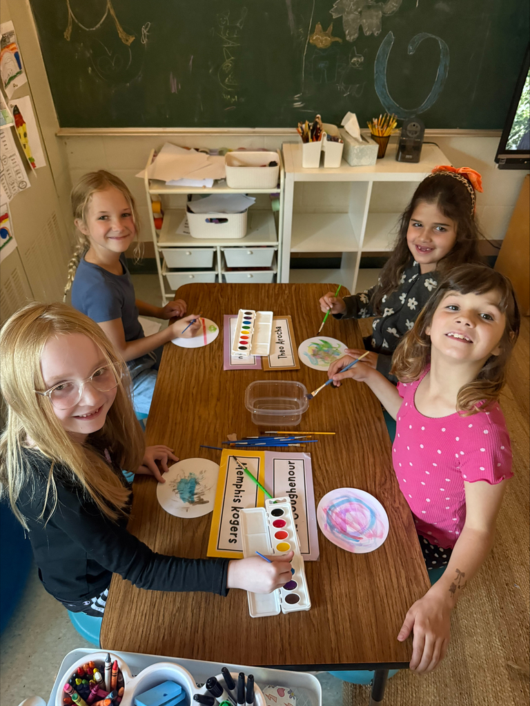 group of students sitting at a table ion a classroom painting with watercolors