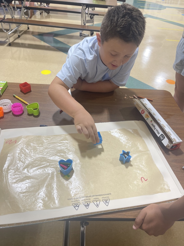picture of a boy using cookie cutters with melted crayons