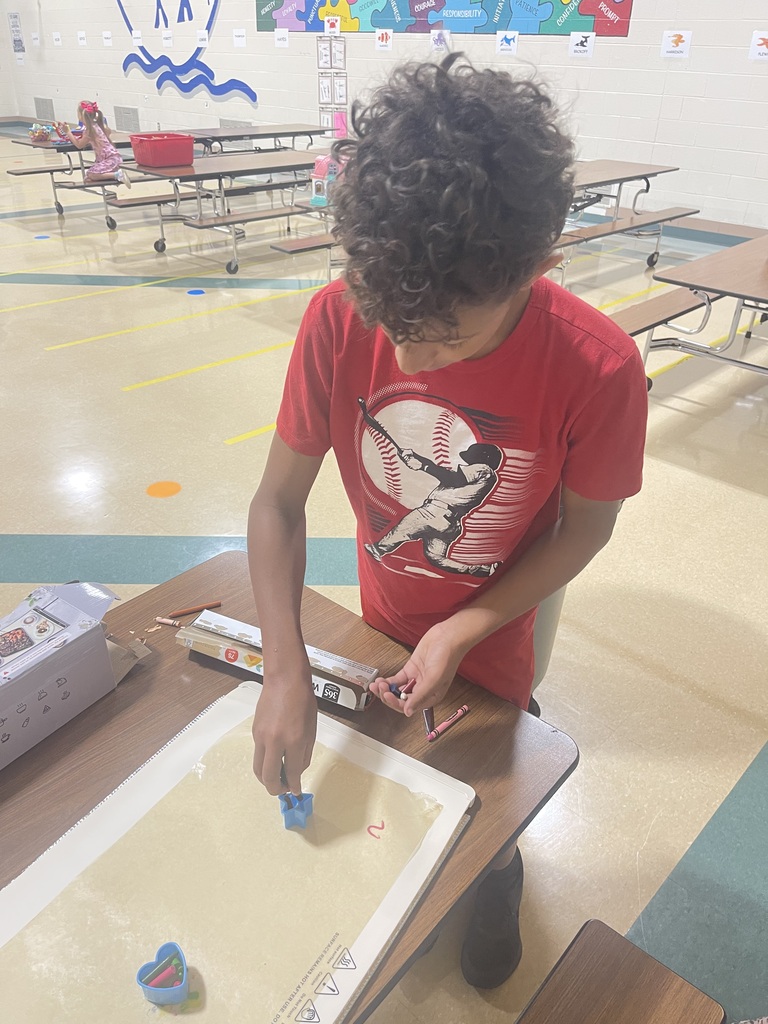 picture of a boy using cookie cutters with melted crayons