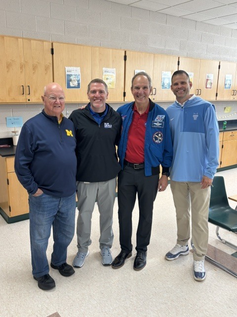 4 men posing in a classroom