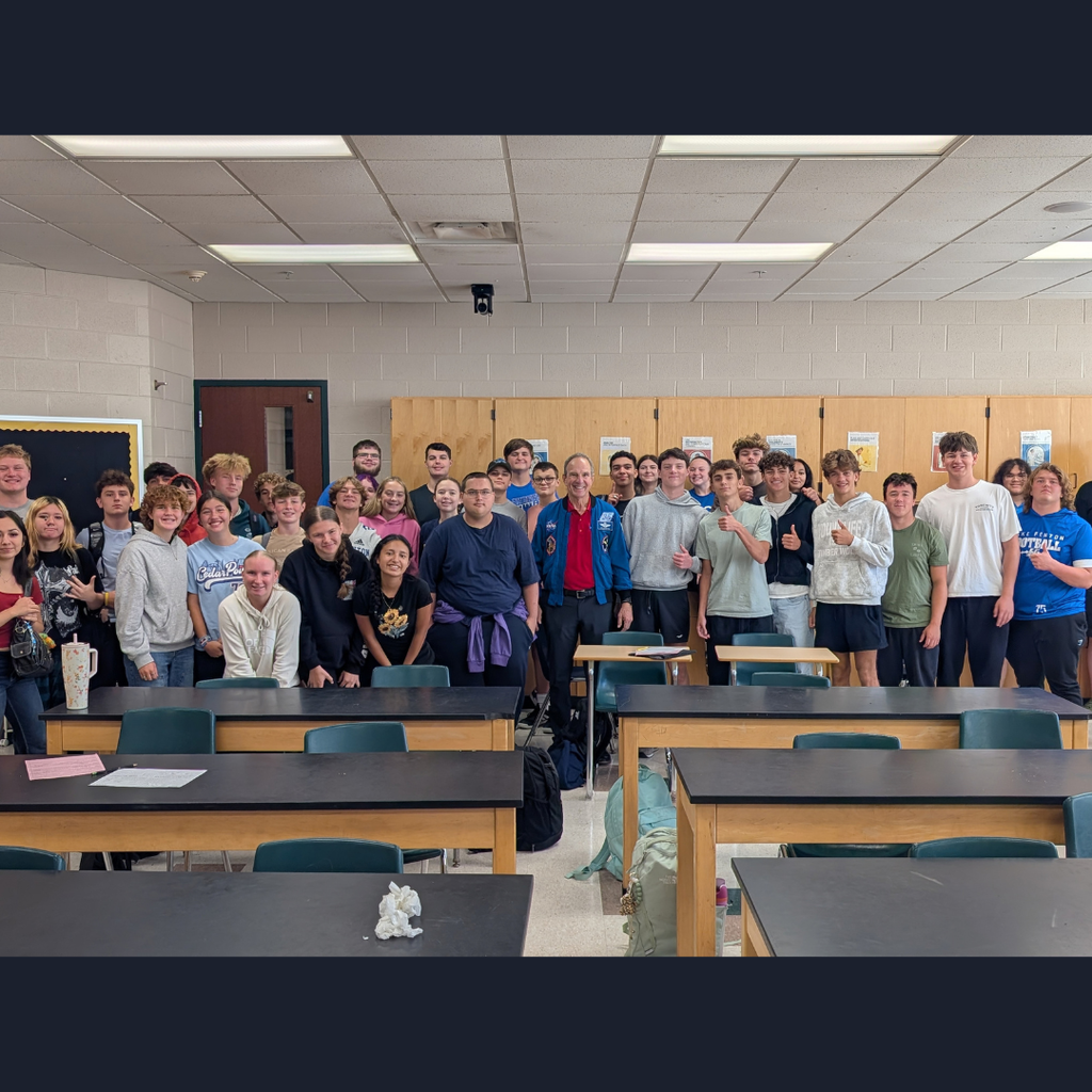 large group of kids posing with a man in a classroom