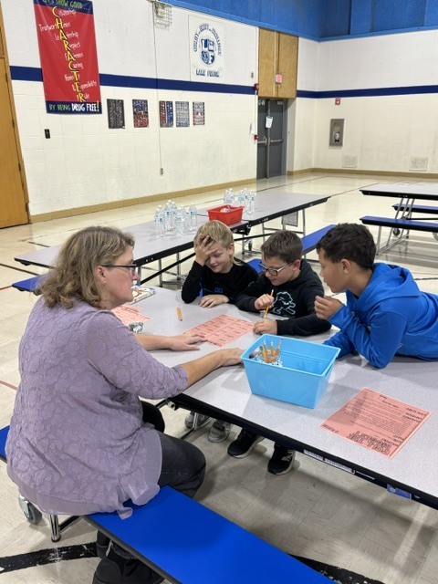 kids at a table with a woman doing school work