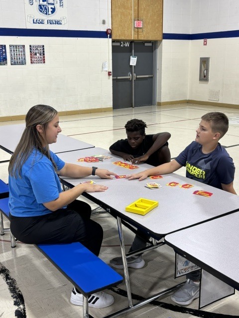 kids at a table with a woman doing school work