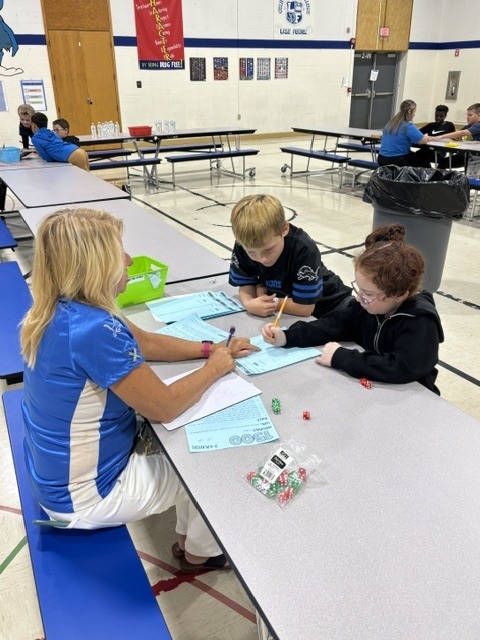 kids at a table with a woman doing school work