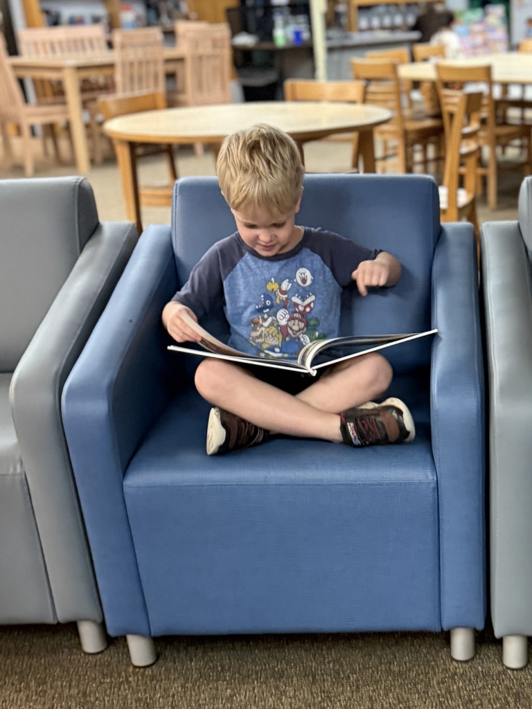 little boy sitting in a chair reading