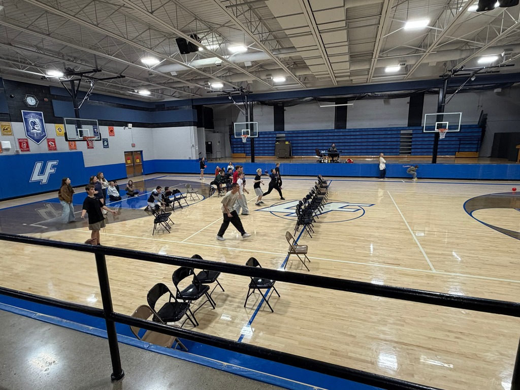 students in a gym with rows of folding chairs