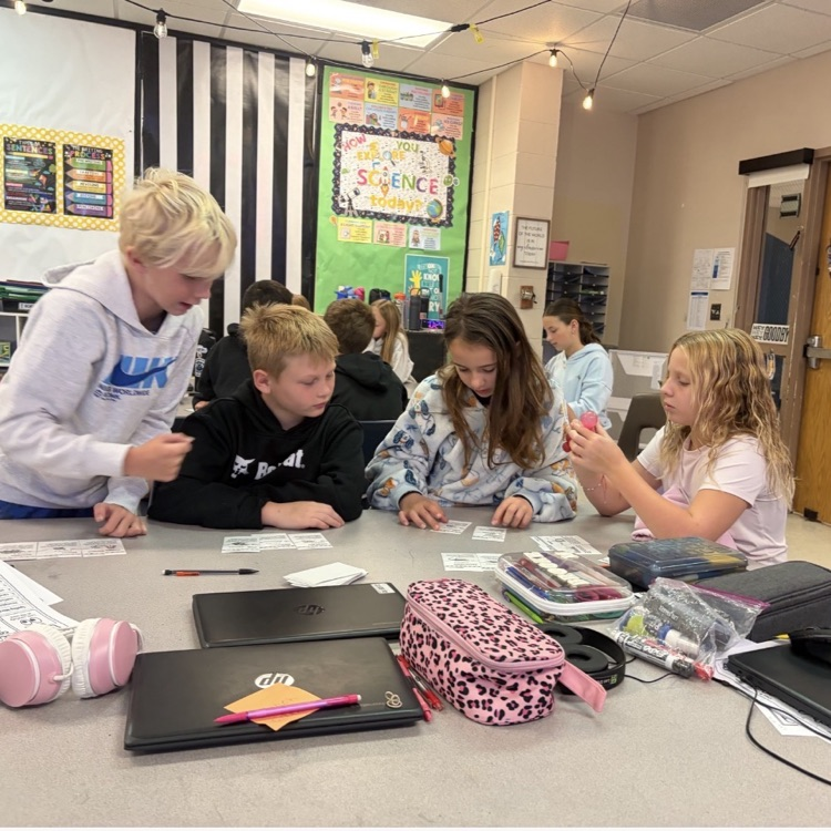 4 children sitting around a desk working with white cards
