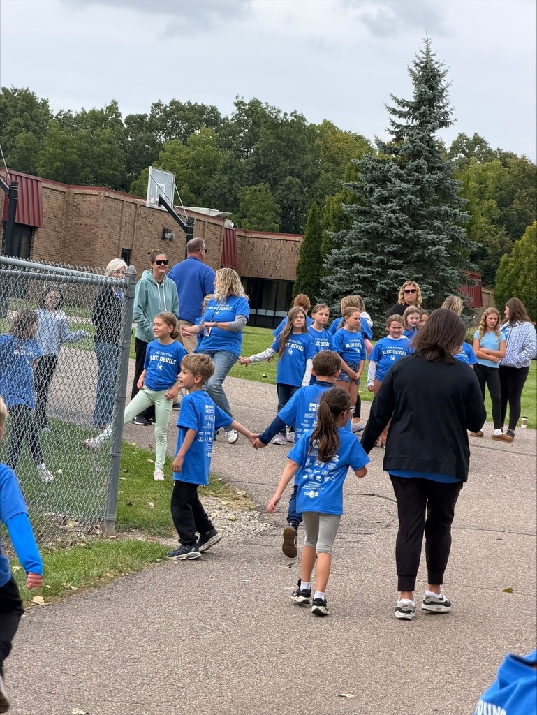 adults and children outside a school wearing blue t-shirts