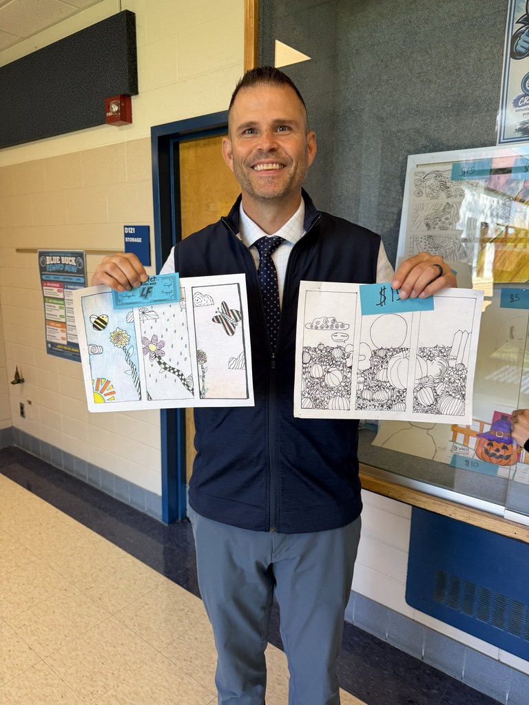 man smiling holding up 2 drawings
