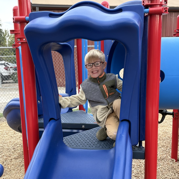 boy smiling on a blue slide