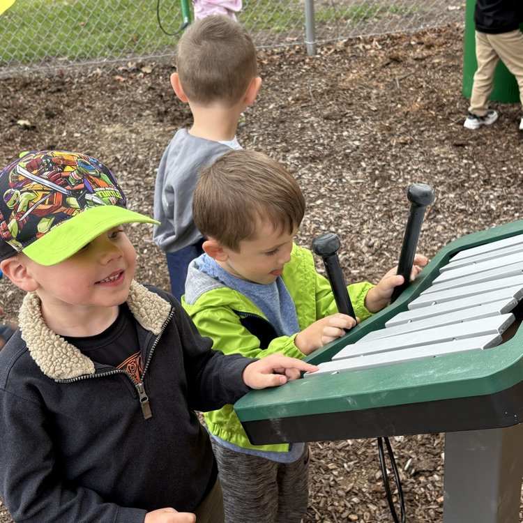 boys playing a large musical instrument on a playground