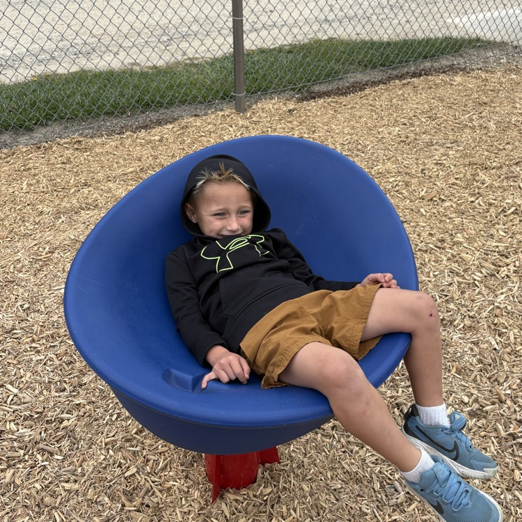 boy sitting in a blue spinner on a playground
