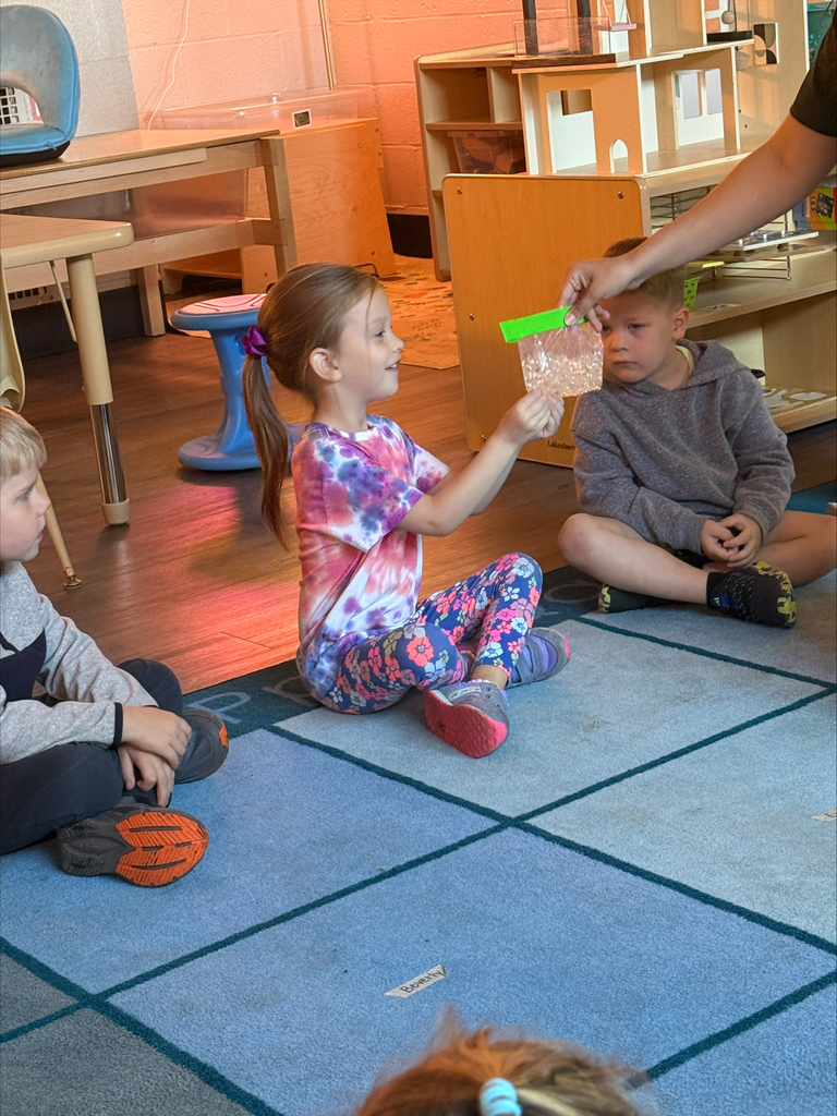 children sitting on a rug looking at a plastic bag