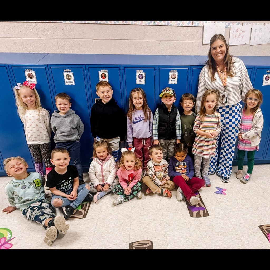 teacher posing with group of kids in front of lockers