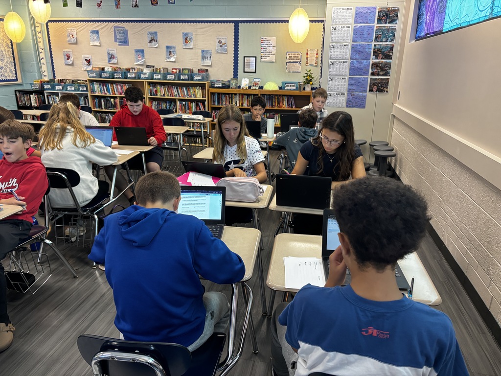 middle school students in a classroom at their desks working on Chromebooks