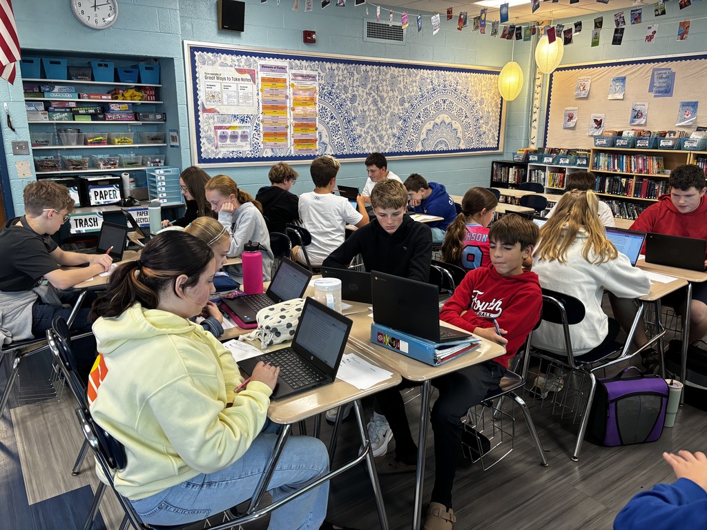 middle school students in a classroom at their desks working on Chromebooks