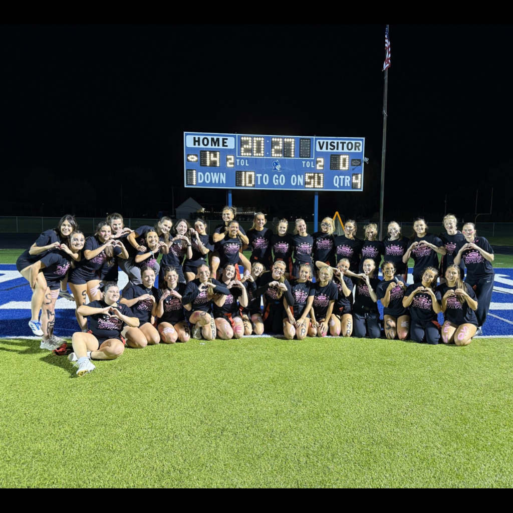 large group of girls posing on a football field in black shirts