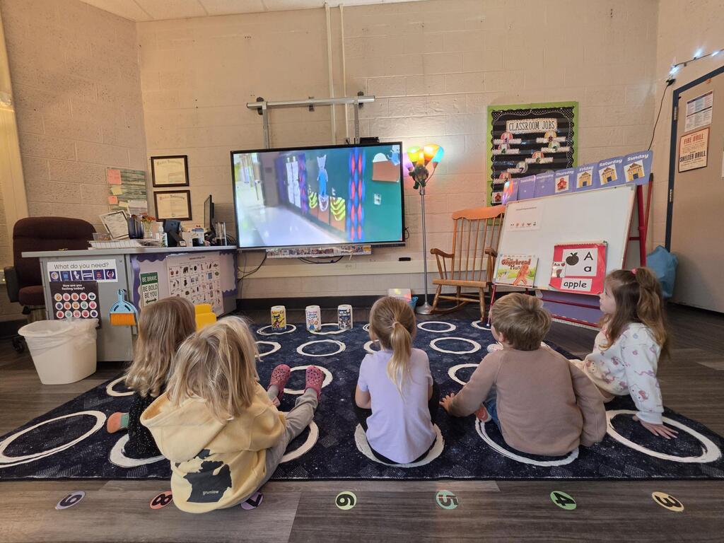 group of students in a classroom watching a large screen