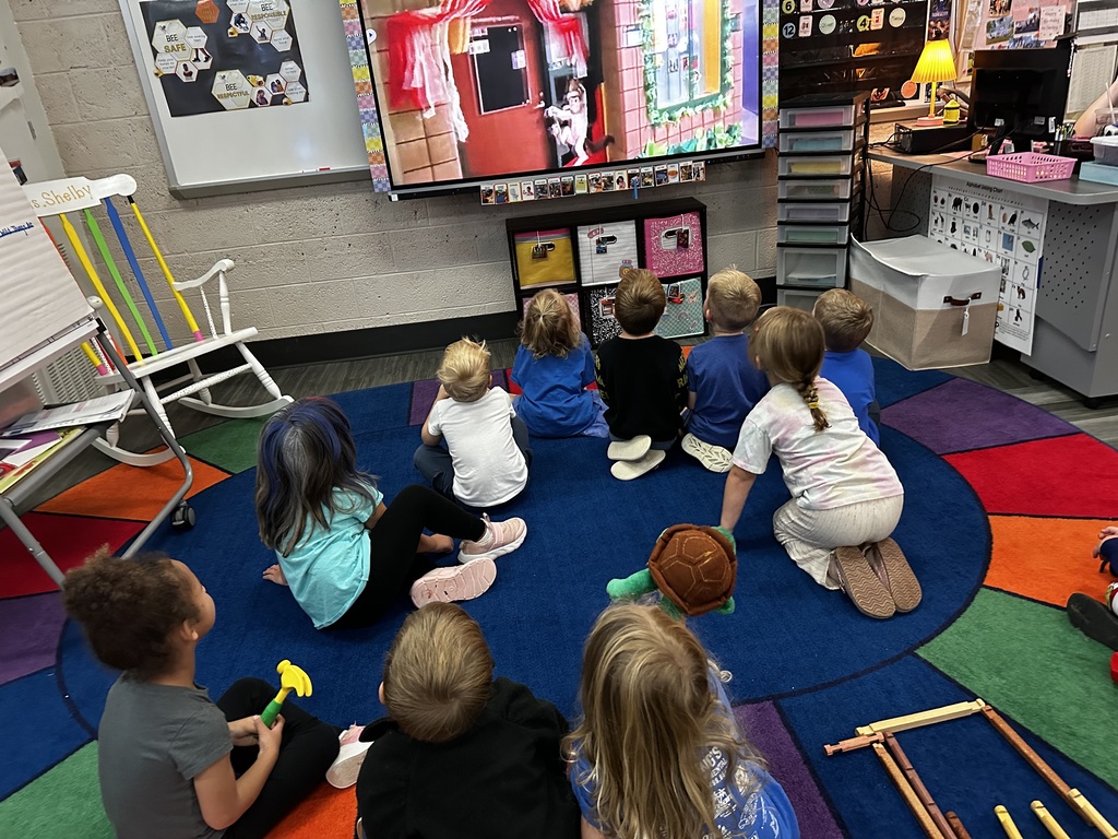 group of students in a classroom watching a large screen