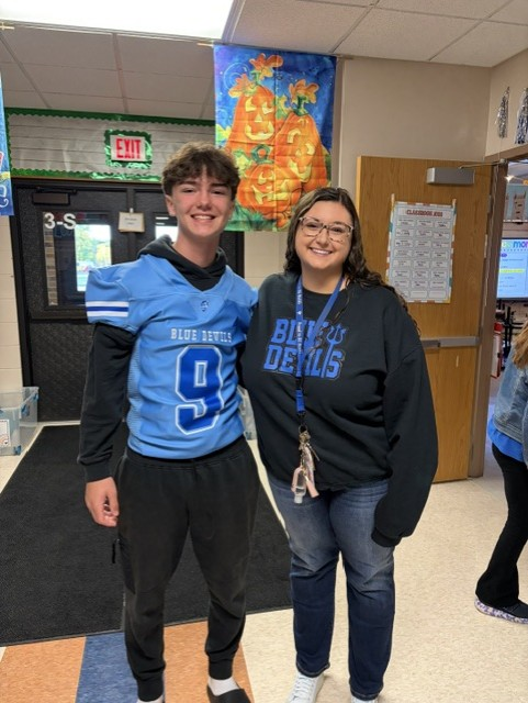 football player in blue jerseys posing with a teacher