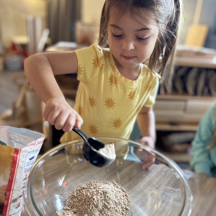 little girl putting powder into a bowl
