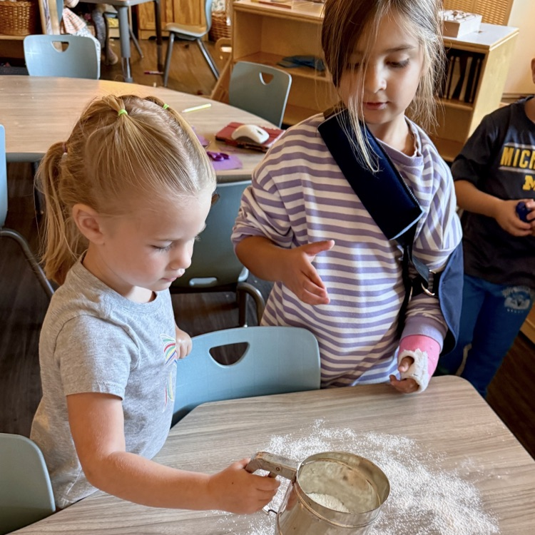 2 preschoolers sprinkling flour