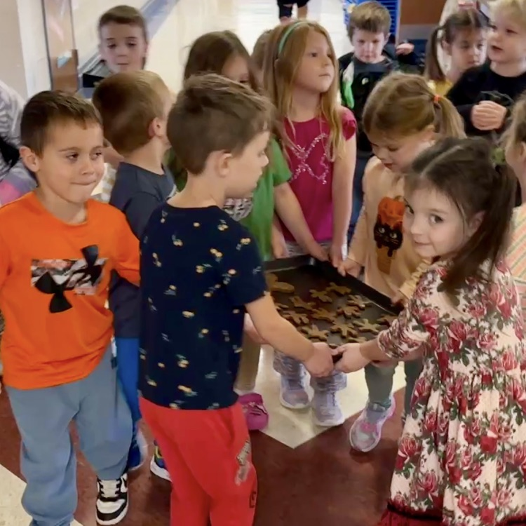 group of preschoolers carrying a tray of gingerbread cookies