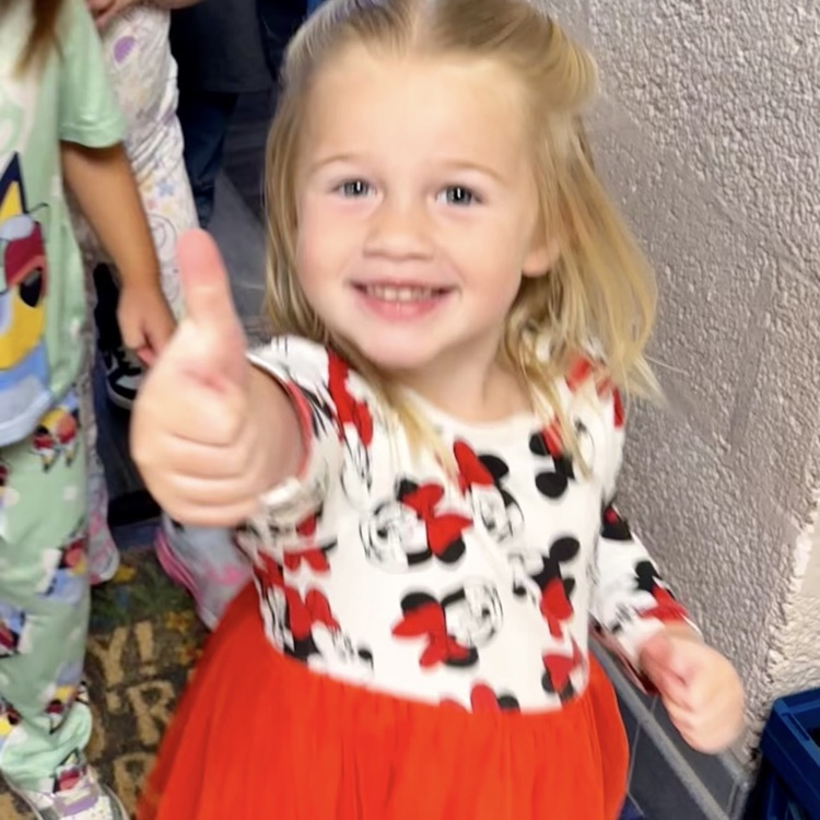 little girl smiling and giving a thumbs up